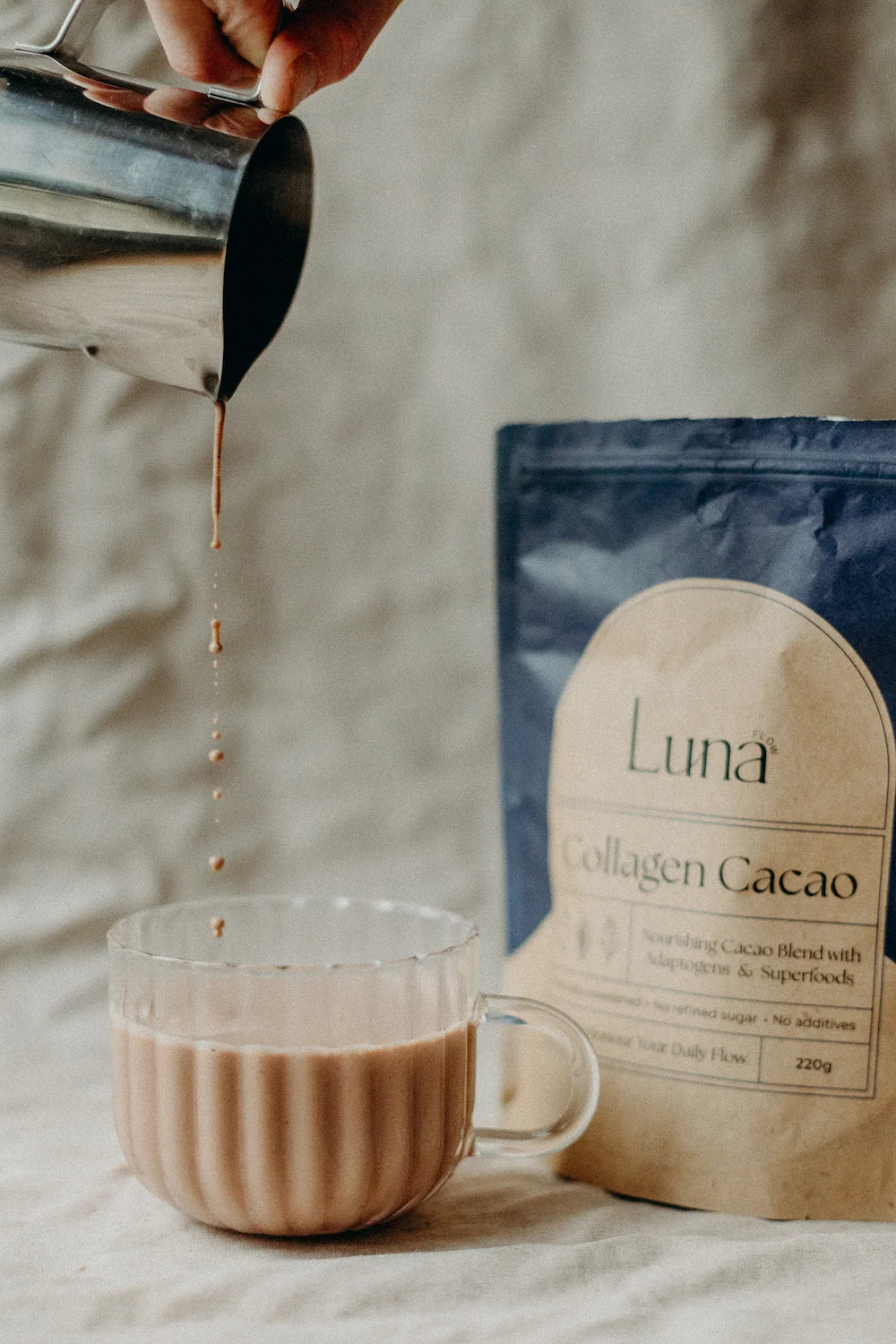 Collagen Cacao being poured into a glass cup next to the bag