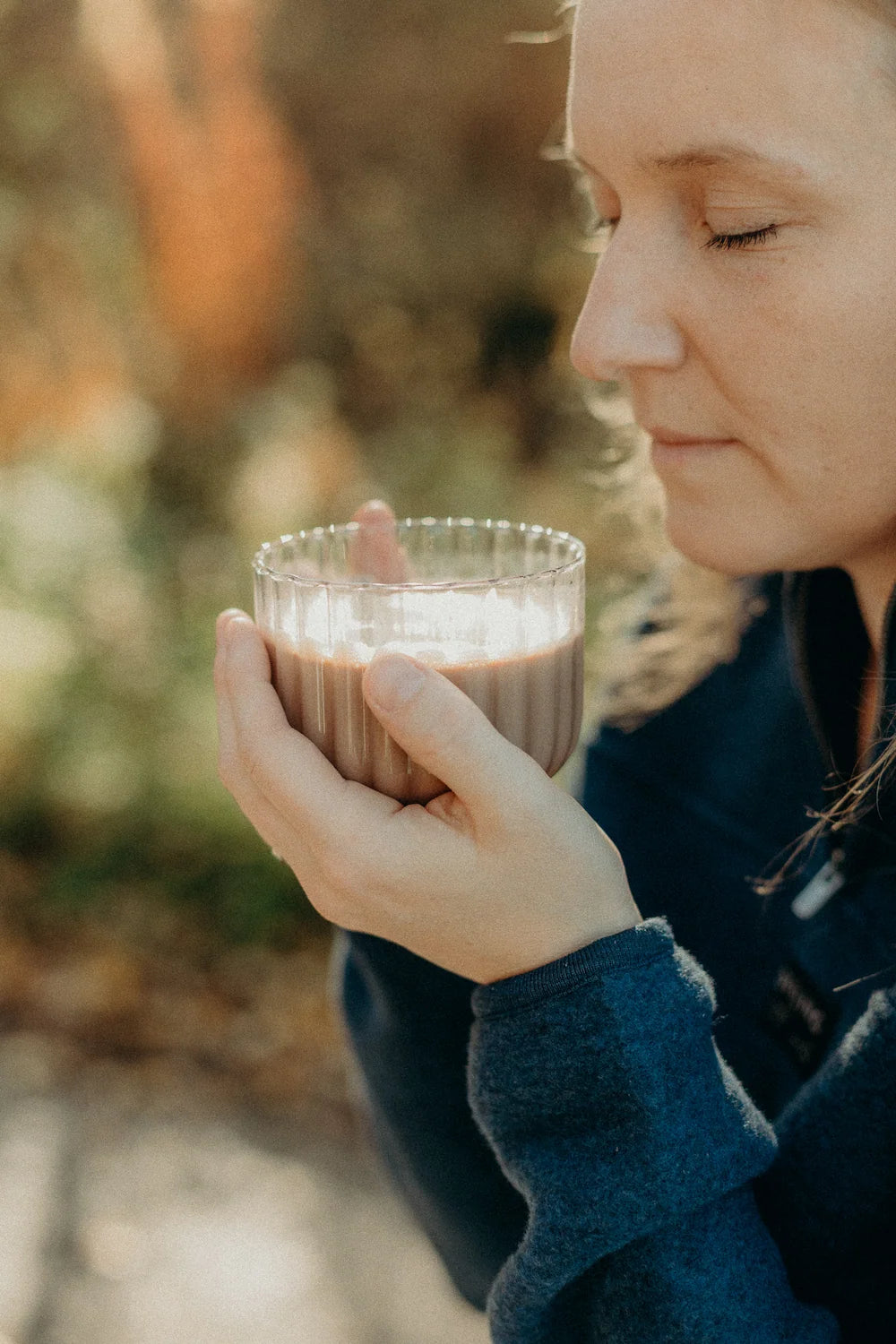 Woman with closed eyes sipping cacao from a glass cup